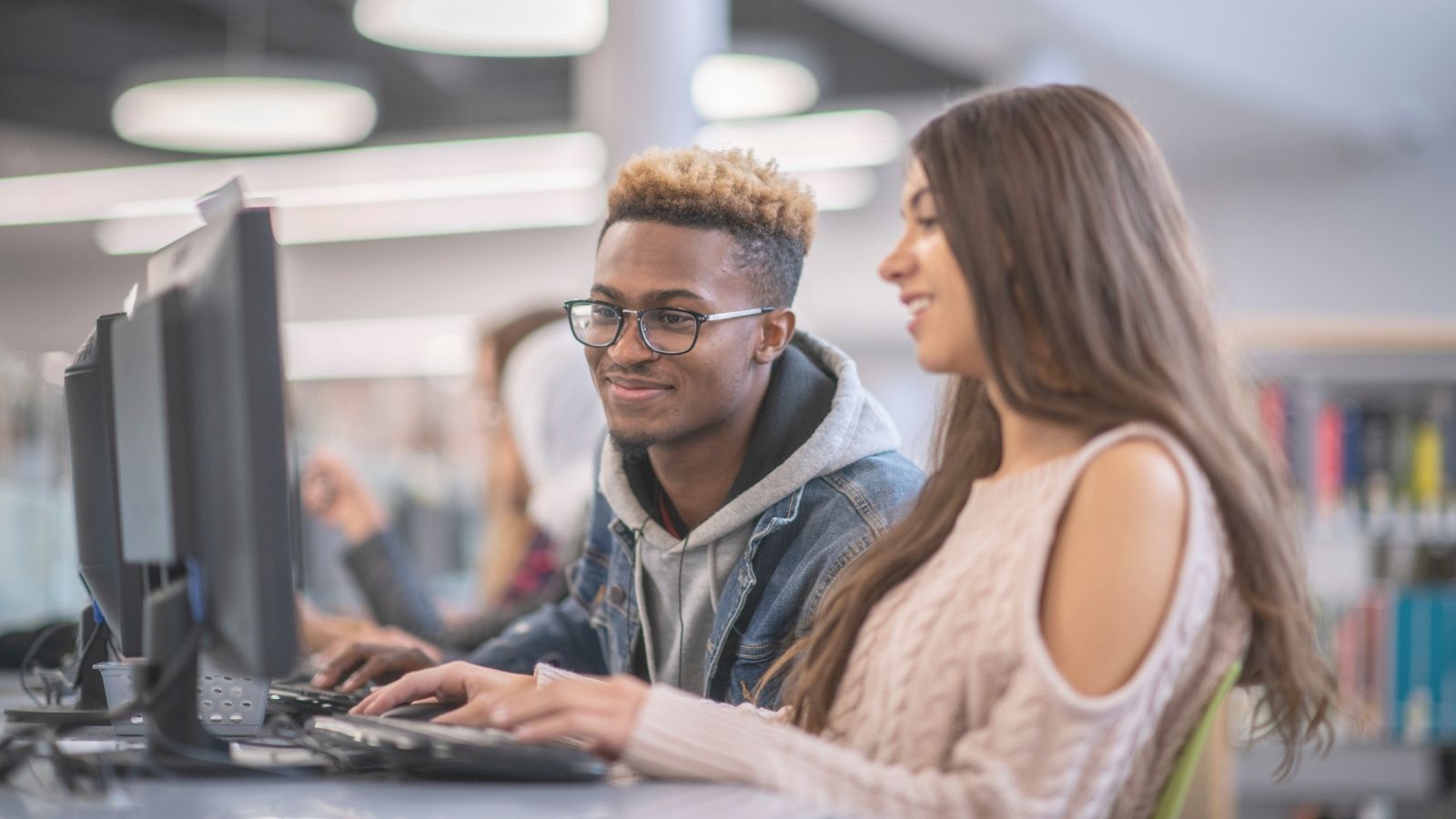 students at desk on computers smiling and conversing
